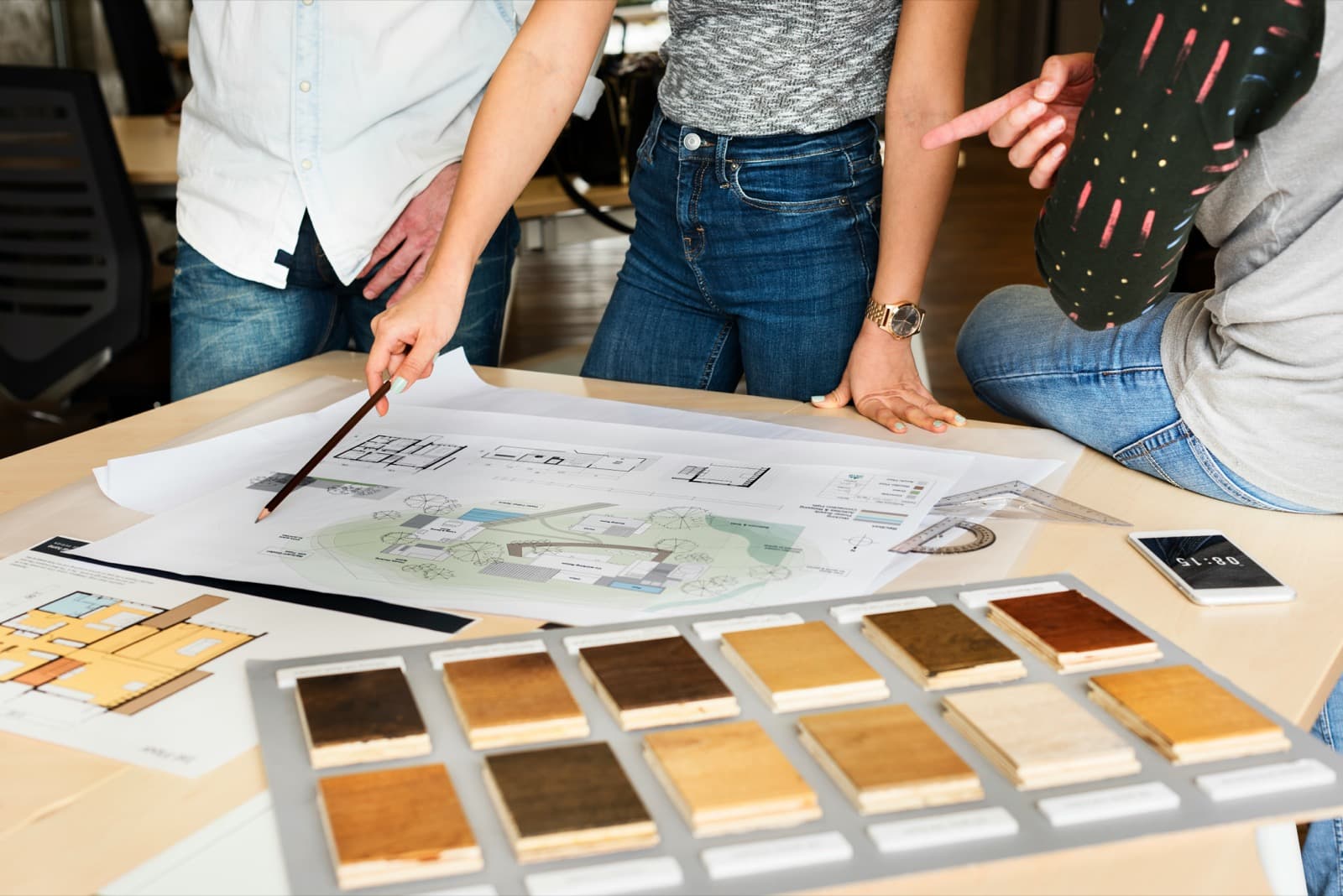 Houtstalen en plannen op tafel tijdens een bespreking van materiaalkeuzes.